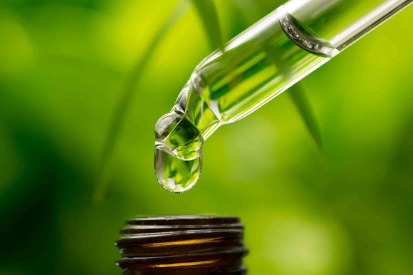 Image of CBD vape oil in bottle with green background of leaves 